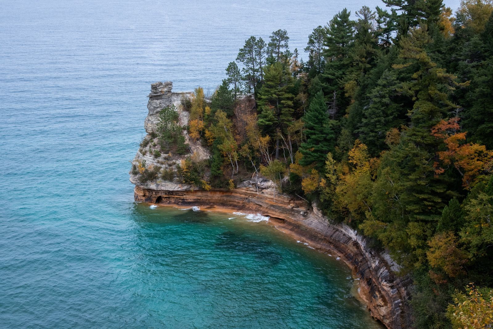 Turquoise water below the forested sandstone cliffs of Pictured Rocks on Lake Superior, scenery on Great Lakes cruises
