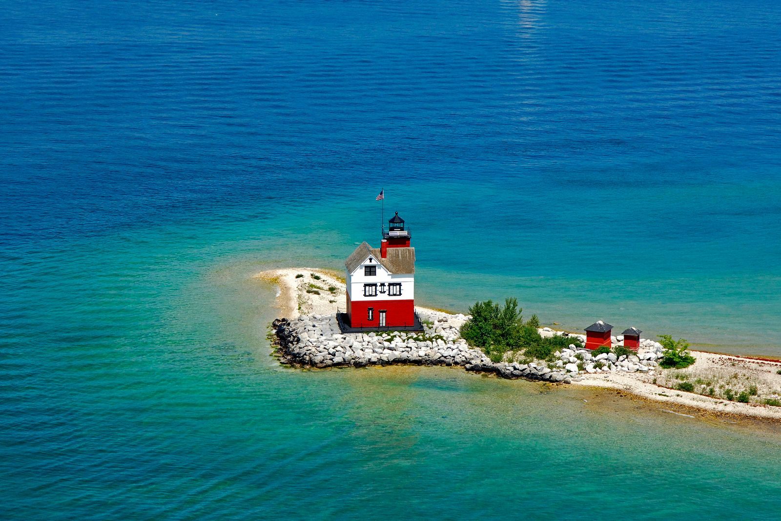 Aerial view of the red Round Island Lighthouse in turquoise water off Mackinac Island